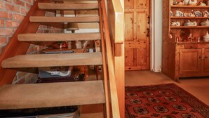 Una escalera de madera con un rellano alfombrado, una puerta de madera y un armario con objetos de cerámica.