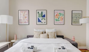 Ein Hotelzimmer mit einem großen Bett, einem Nachttisch, einer Lampe und Kunstwerken an der Wand.