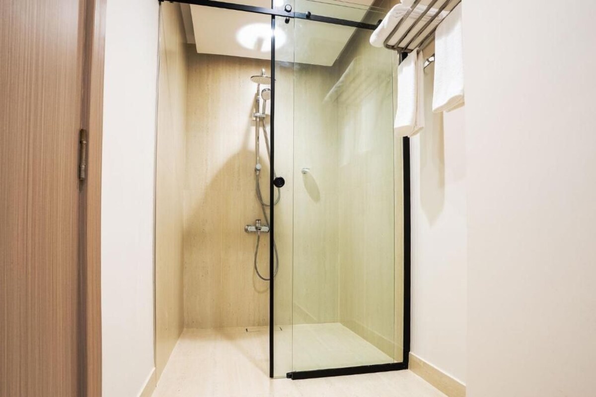 Une salle de douche entièrement vitrée, avec un plancher en bois et un mur blanc.