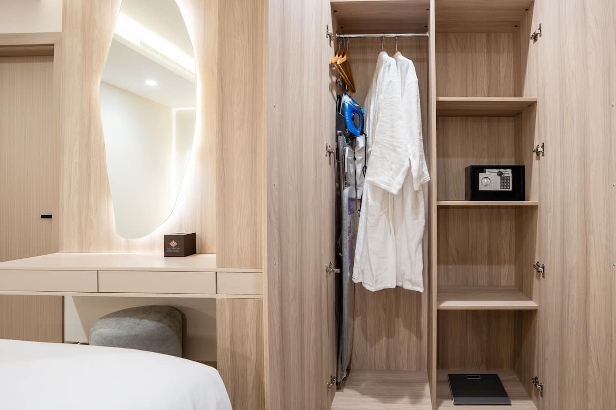 A modern bedroom with a wooden wardrobe, a vanity with a mirror, and a neatly made bed.