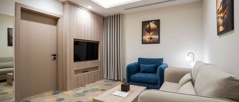 A modern living room with a sofa, a coffee table, a TV, and a large window with curtains.