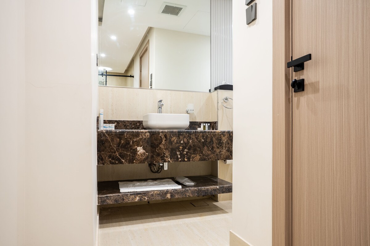 A bathroom with a marble countertop, a sink, and a mirror.