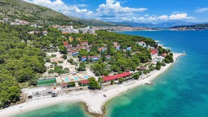 A coastal town with a beach, buildings, and a mountainous backdrop.