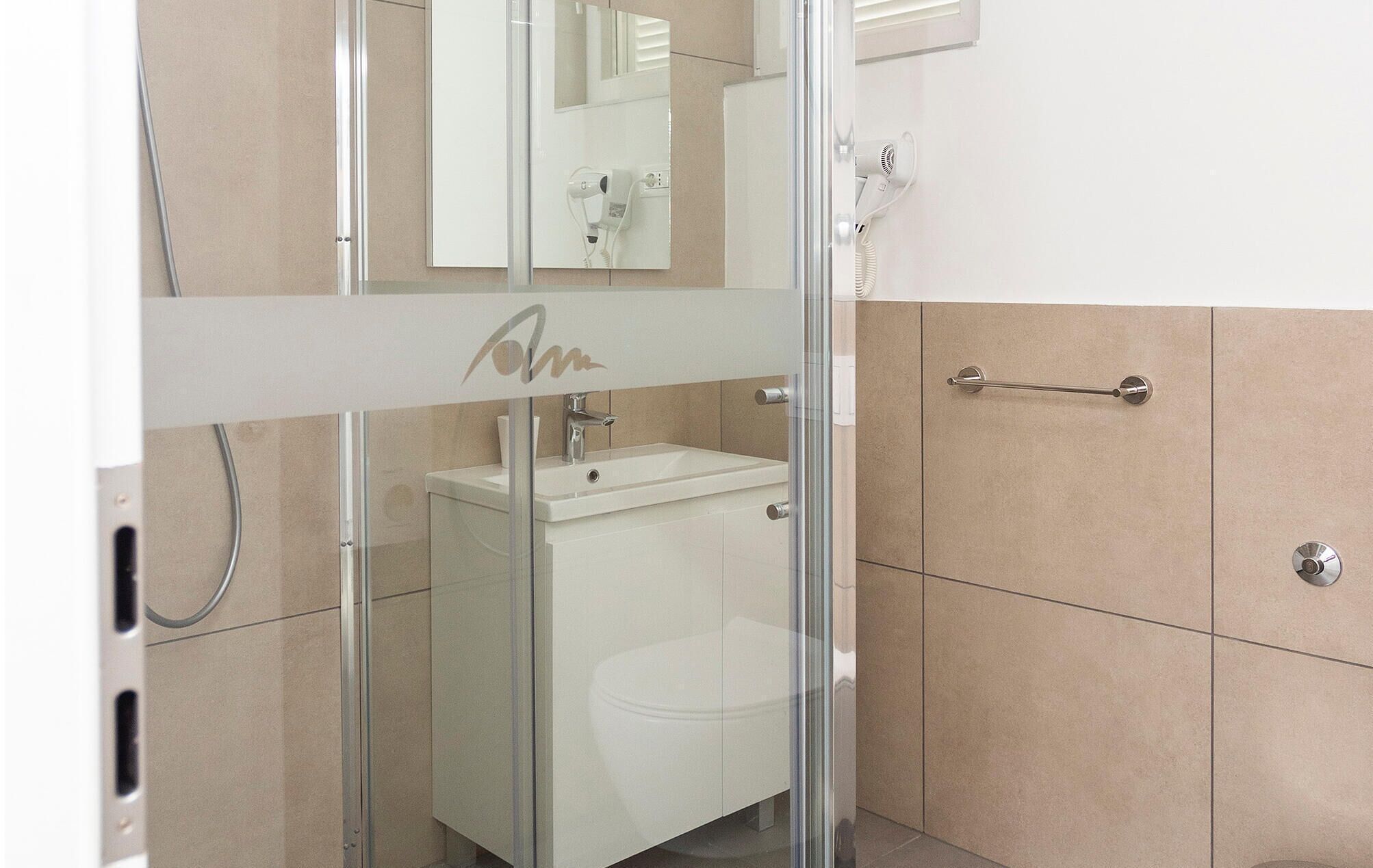 Un bany modern amb una cabina de dutxa de vidre, un lavabo blanc i un vàter.