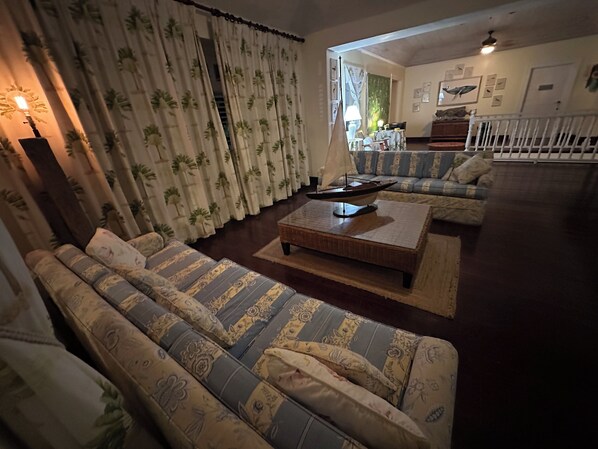 A living room with patterned sofas, a coffee table, and a sailboat model.