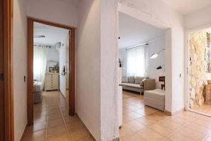 A hallway leading to a living area with a sofa and a lamp.