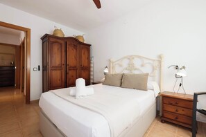 A bedroom with a bed, wooden wardrobe, bedside table, and a lamp. - Golf • Mas Vilet - Unik Vacation (El Catllar)