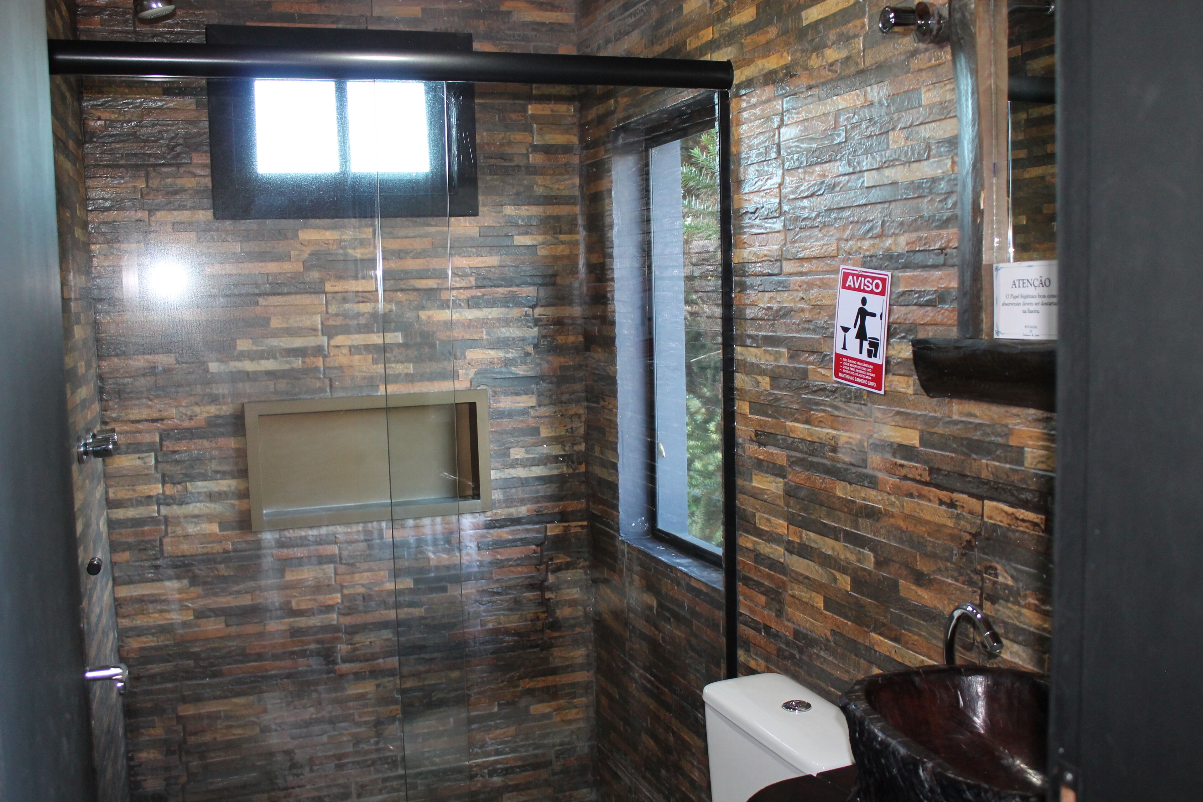 A bathroom with a stone wall, a window, a sink, and a toilet.