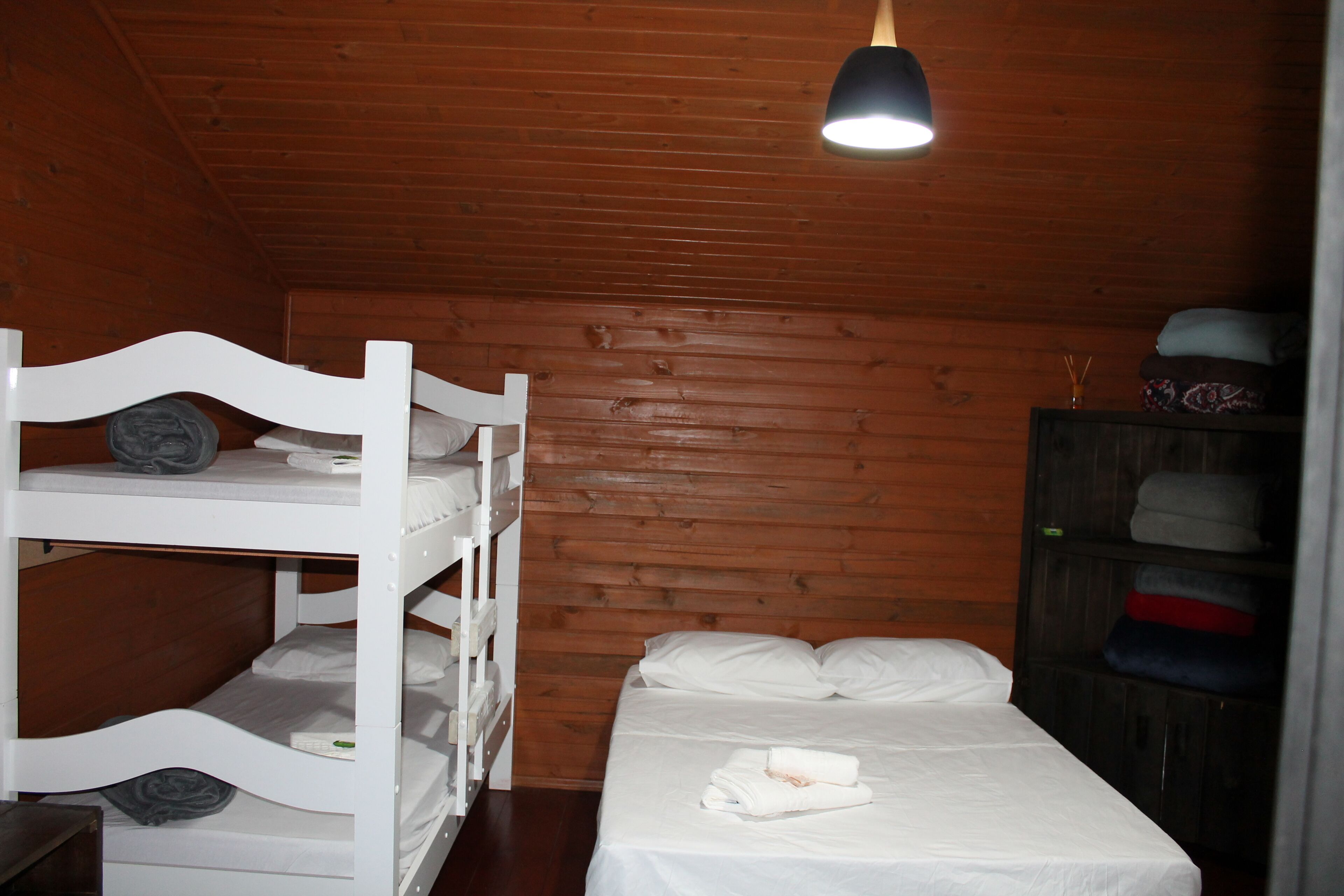 Une chambre avec un lit superposé, un lit simple et une armoire.