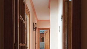 A hallway with wooden doors, a light fixture, and a view into a room with a sink and cabinets. - Grandfather's house (Ítrabo)
