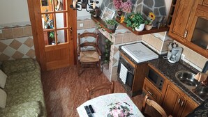 Une cuisine compacte avec un mur en pierre, des placards en bois, une table à manger équipée de télécommandes et une chaise.