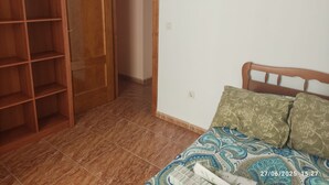 A bedroom with a bed, a wardrobe, and a tiled floor. - Grandfather's house (Ítrabo)