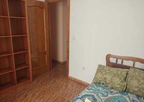 A bedroom with a bed, a wardrobe, and a tiled floor. - Grandfather's house (Ítrabo)