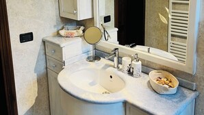 A bathroom with a sink, mirror, vanity, and towel rack. - Mary House (Bottai)