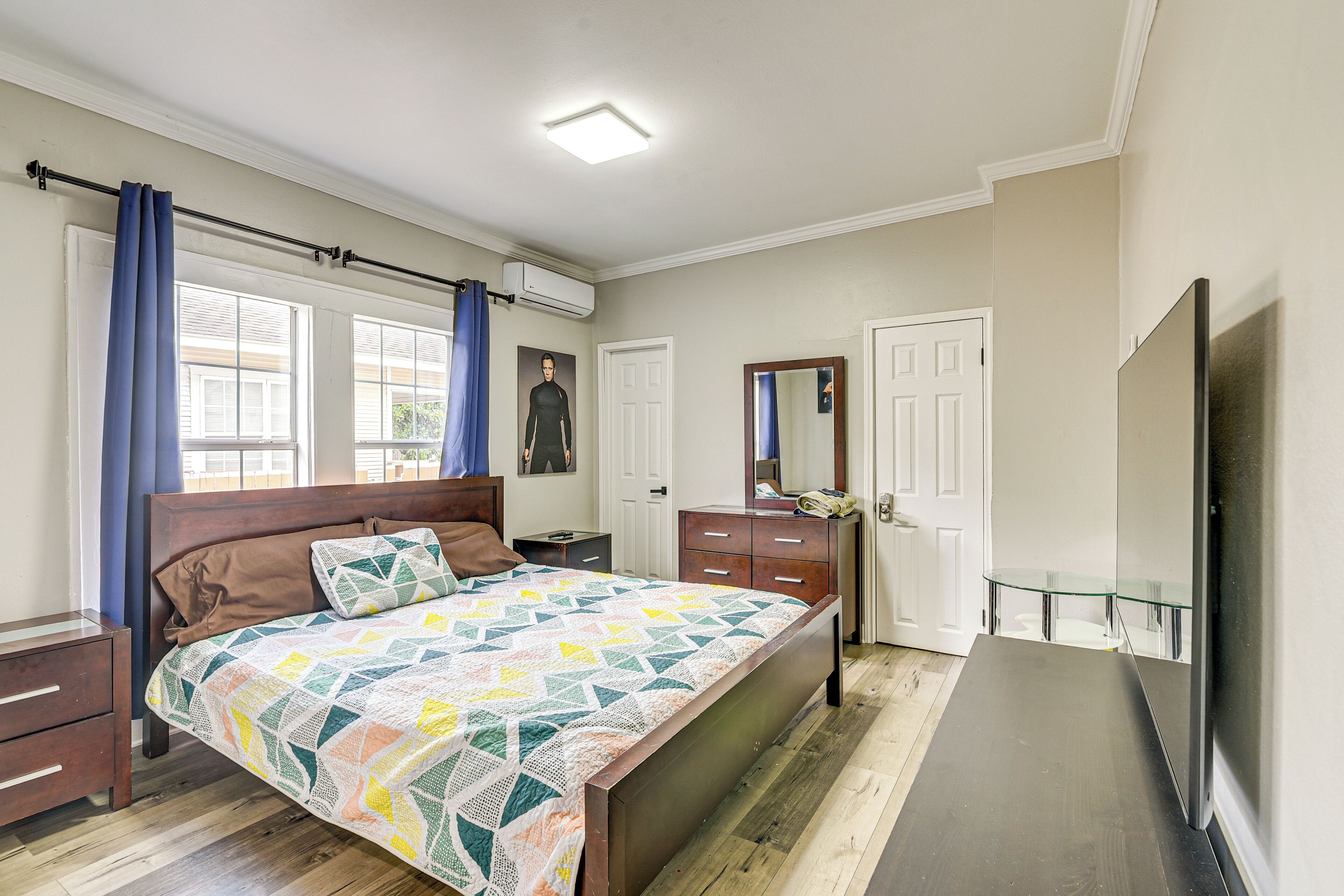 A bedroom with a bed, a dresser, a mirror, and a television.