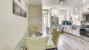 A modern kitchen with white cabinets, stainless steel appliances, and a glass dining table with chairs. - Walk to Harrisburg Blvd: East Downtown Houston Apt (Houston)