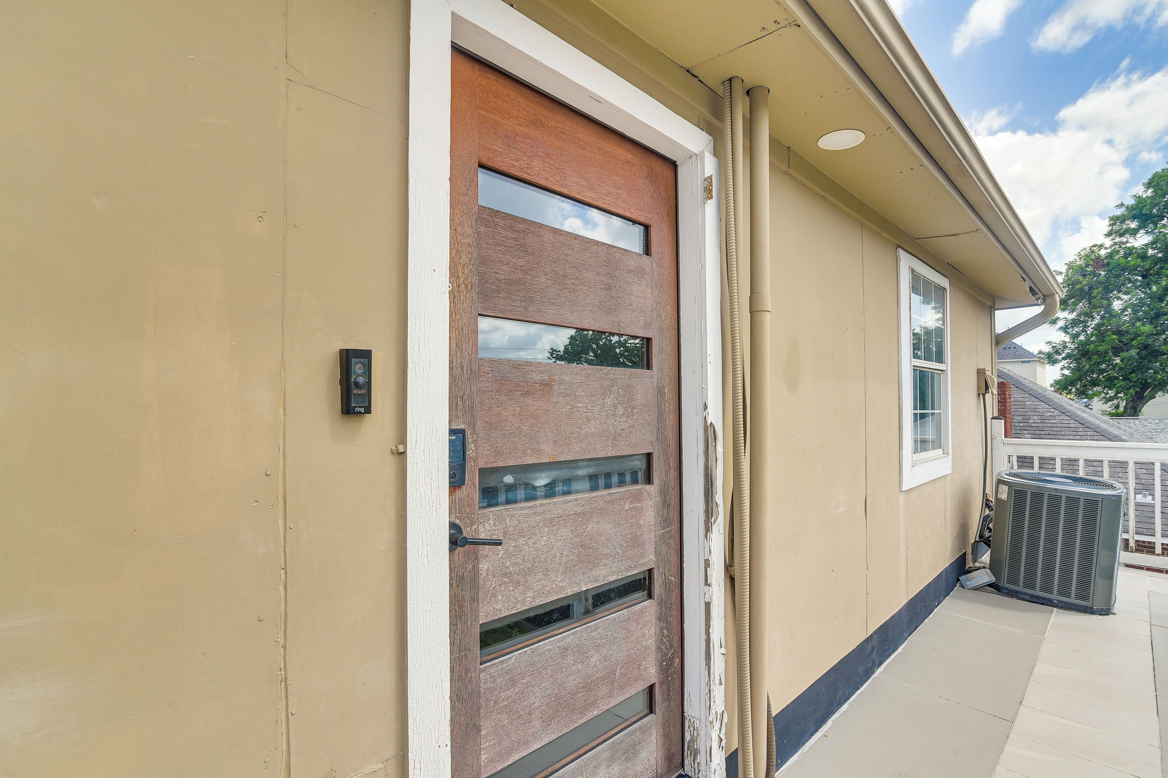 A beige exterior wall with a wooden door featuring multiple glass panels and a metal handle.