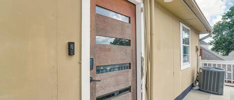 A beige exterior wall with a wooden door featuring multiple glass panels and a metal handle.