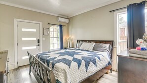 Un dormitorio con cama, cómoda, puerta y ventana.
