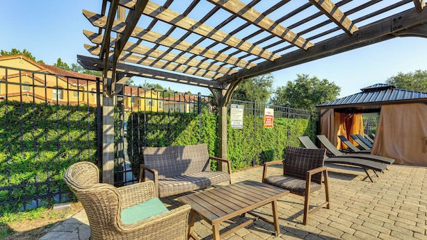 An outdoor patio area with wicker furniture, a pergola, and a view of a building in the background. - 2 Mi to Wdw: Townhouse w/ Patio & Pool Access (Kissimmee)