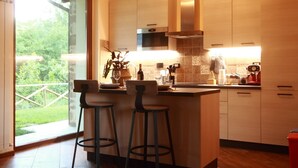 Una cocina moderna con una isla grande, dos taburetes de bar y vistas al jardín a través de un ventanal.
