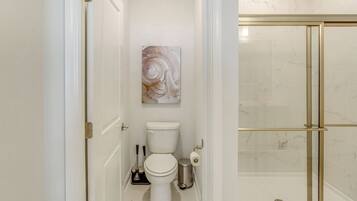 A bathroom with a toilet, a sink, and a shower area.