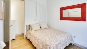 A bedroom with a bed, a door, a white curtain, and a red-framed mirror on the wall. - Shop, Dine & Walk to Ocean: Redondo Beach Apt! (Redondo Beach)