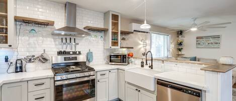 A modern kitchen with white cabinetry, stainless steel appliances, and a blue patterned rug.