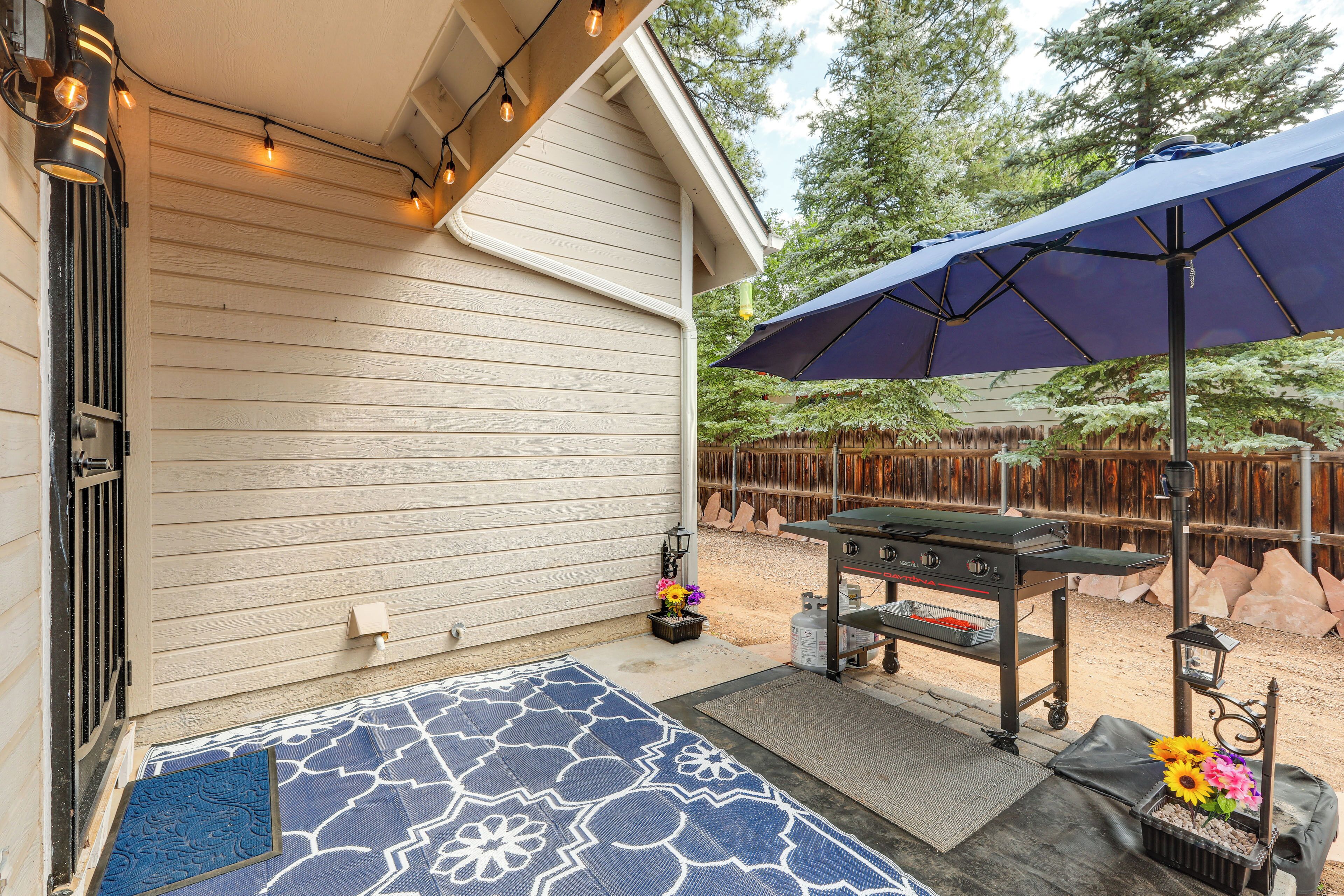 Une terrasse couverte équipée d’un barbecue, d’un éclairage extérieur et agrémentée d’un tapis décoratif.