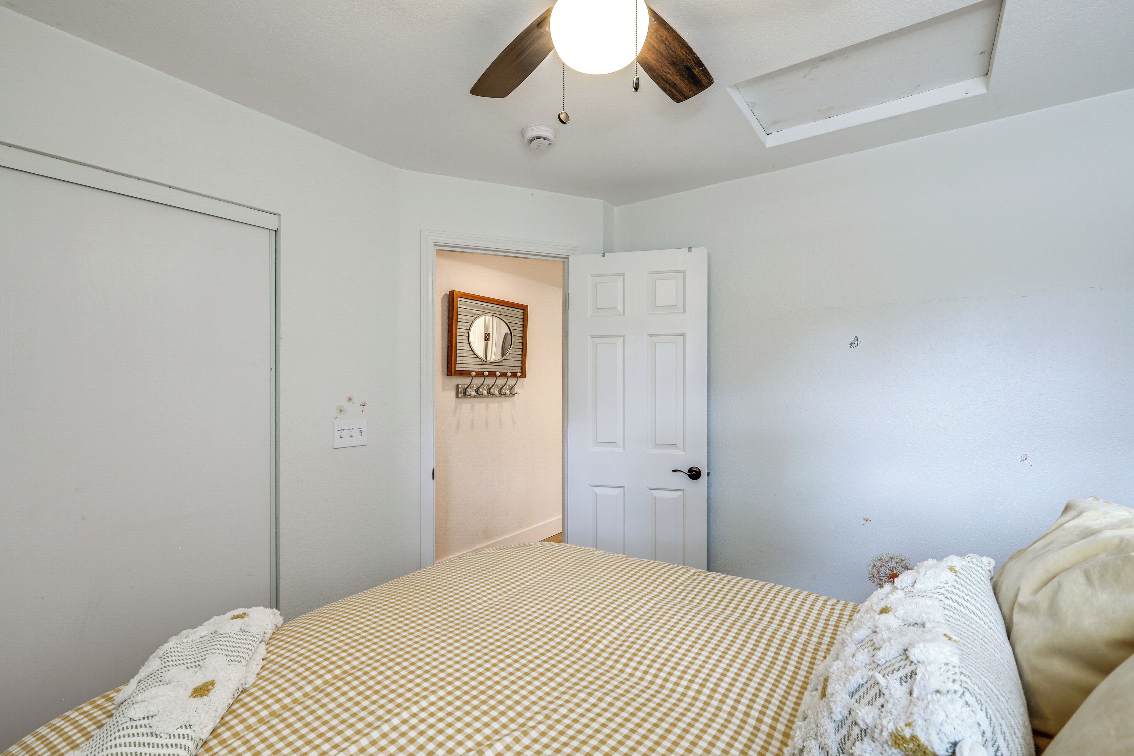 Een slaapkamer met een bed, een plafondventilator, een deur en een klok aan de muur.