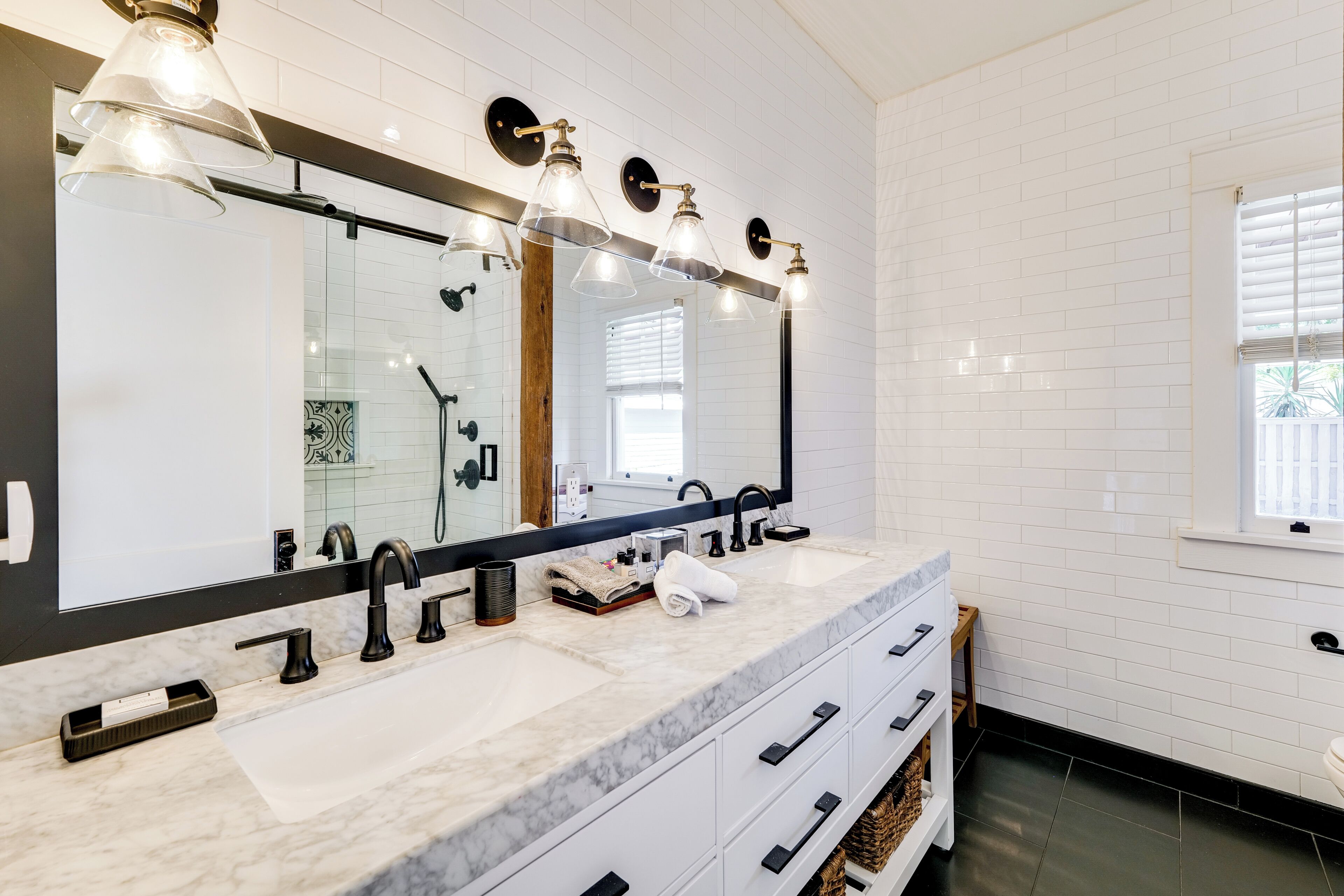 A modern bathroom with a large mirror, two sinks, and a vanity with drawers.