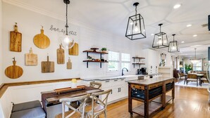 Een moderne keuken met houten snijplanken aan de muur, een centraal eiland en hangende lampen.