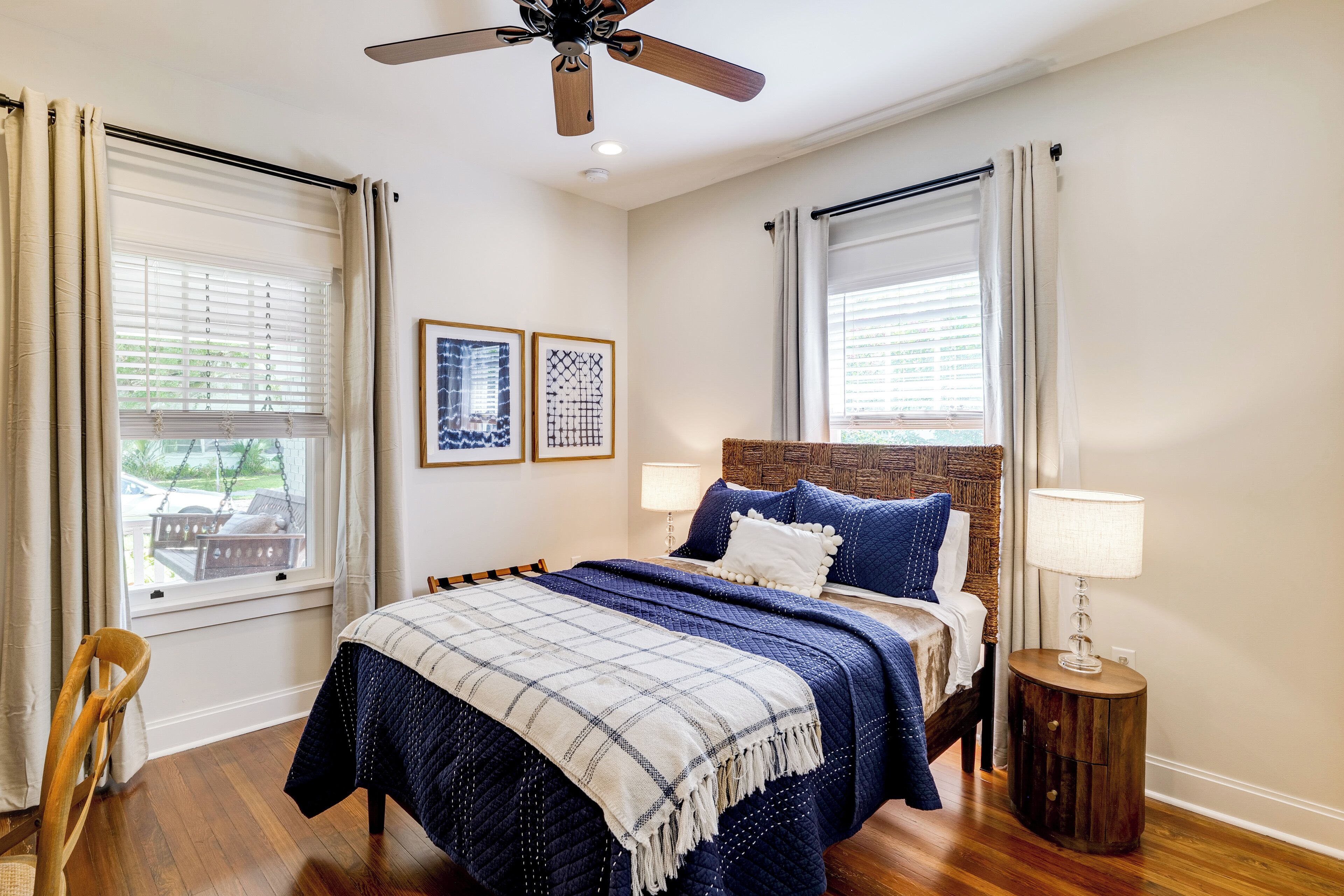 A bedroom with a bed, two bedside tables, a ceiling fan, and a window with curtains.