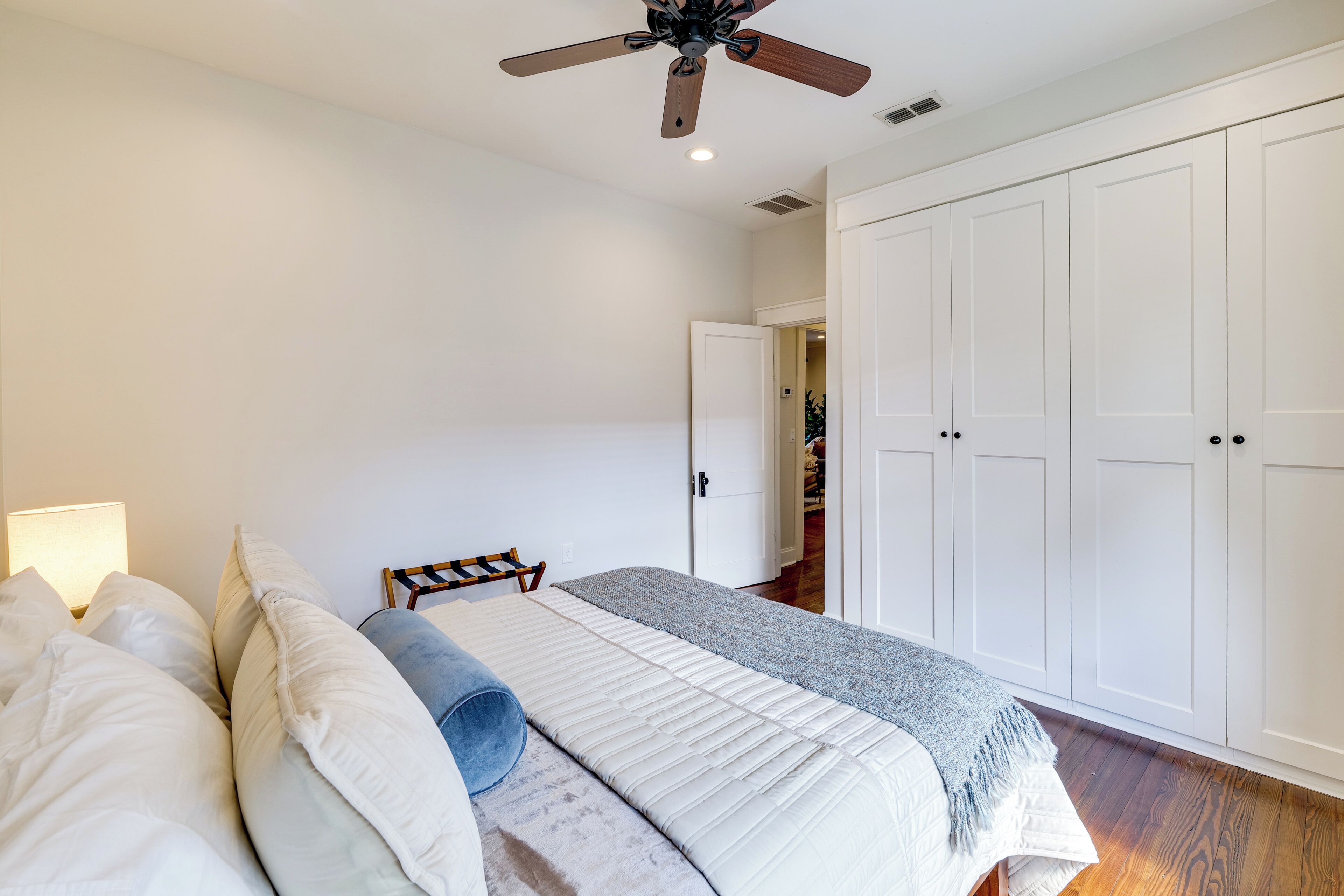 A bedroom with a bed, a ceiling fan, a nightstand, and a wardrobe.