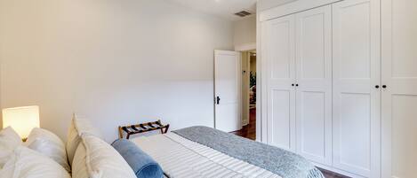 A bedroom with a bed, a ceiling fan, a nightstand, and a wardrobe.