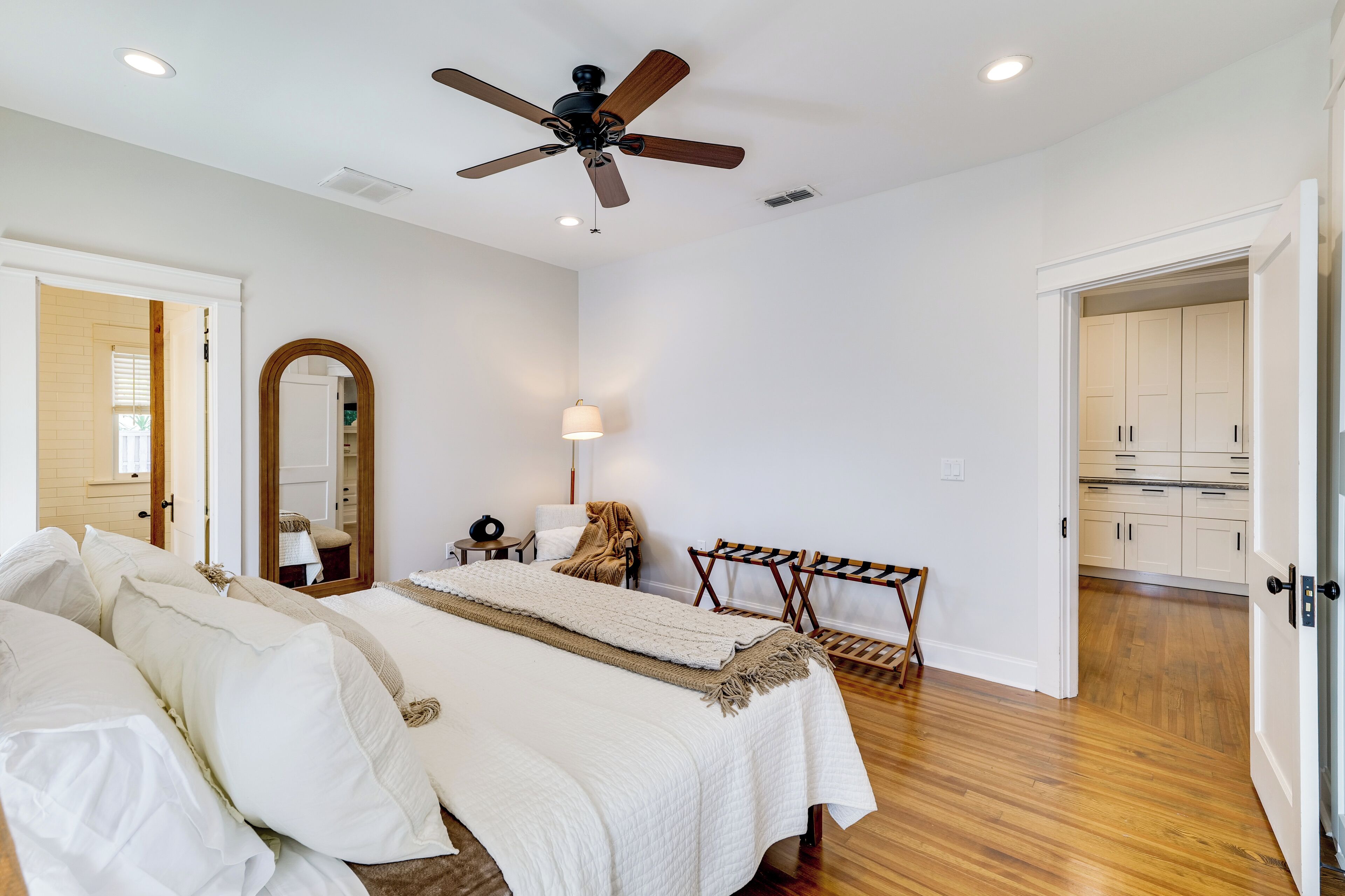 A bedroom with a bed, a ceiling fan, a mirror, and a wardrobe.