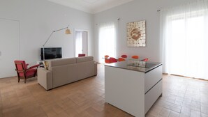 A modern living room with a sofa, a red chair, a TV, and a small island with chairs.