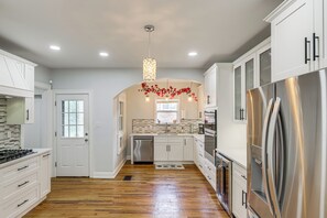 A modern kitchen with white cabinetry, stainless steel appliances, and a wooden floor. - Modern Group Getaway w/ Private Yard in Cincinnati (Cincinnati)
