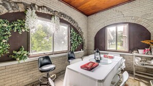 Un coin repas avec un mur en briques, une table blanche, des chaises noires et une boîte rouge posée sur la table.
