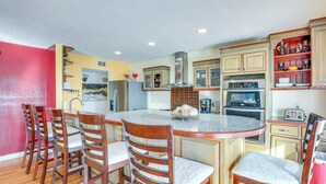 A kitchen with a central island, wooden chairs, and built-in cabinets. - 13 Mi to Downtown El Paso: Home w/ Game Room & Bar (El Paso)