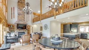 A spacious living area with a fireplace, a dining table, and a kitchen with modern appliances. - Hot Tub, Game Room! 3-story Brian Head Home (Brian Head)
