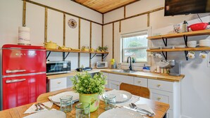 Una cocina con vigas de madera, un refrigerador Galanz rojo, un microondas, un lavamanos y una mesa de comedor con platos y cubiertos.