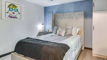 A bedroom with a large bed, a nightstand, a wall-mounted lamp, and a ceiling fan.