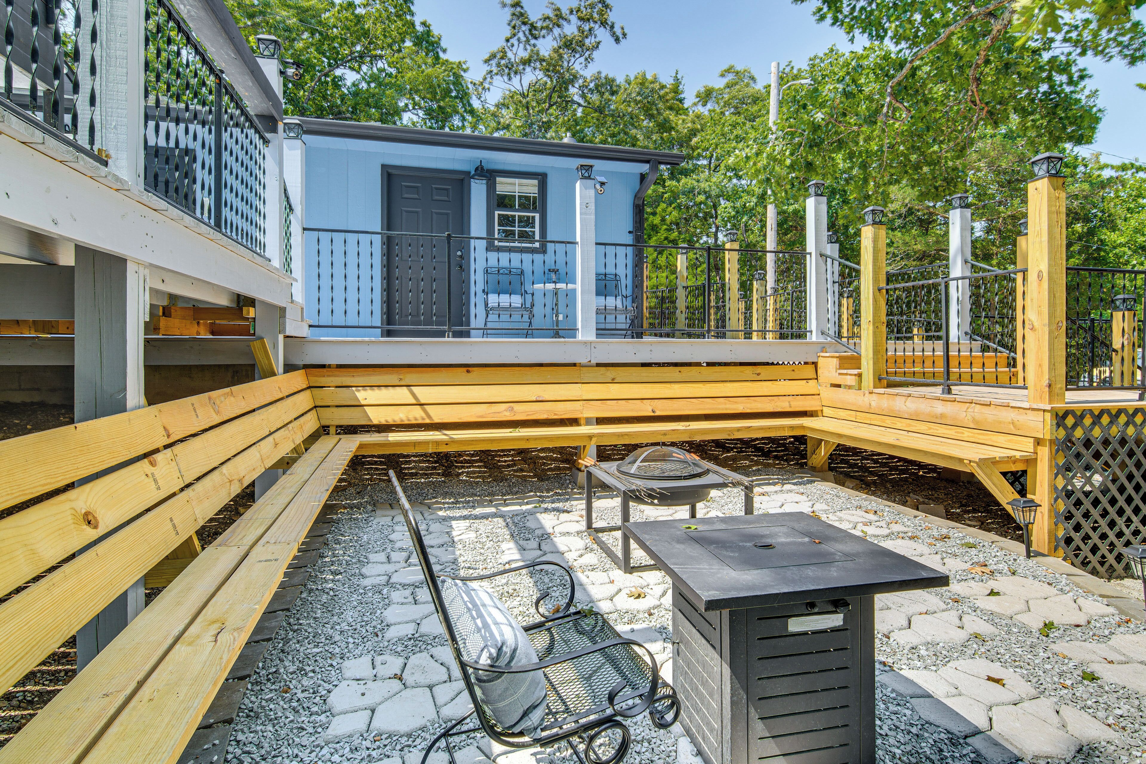 A patio area with a wooden bench, a metal chair, and a small table.