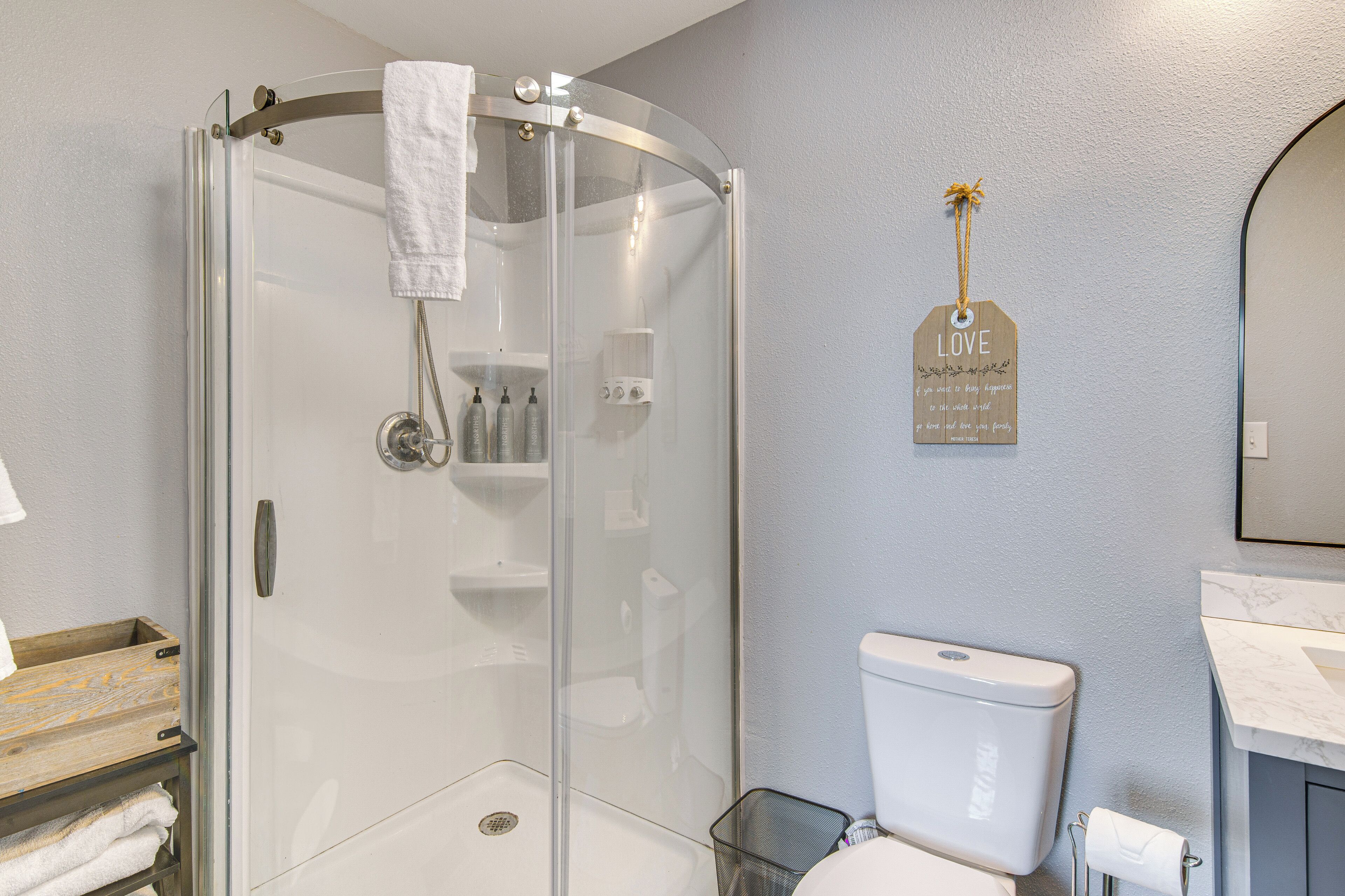 A modern bathroom with a glass-enclosed shower, a toilet, and a sink.