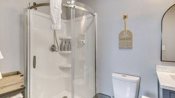 A modern bathroom with a glass-enclosed shower, a toilet, and a sink.