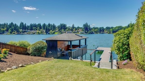 A lakeside property with a dock, a small wooden structure with a deck, and a grassy area. - Waterfront Gem w/ Boat Dock & Lift in Lakewood! (Lakewood)