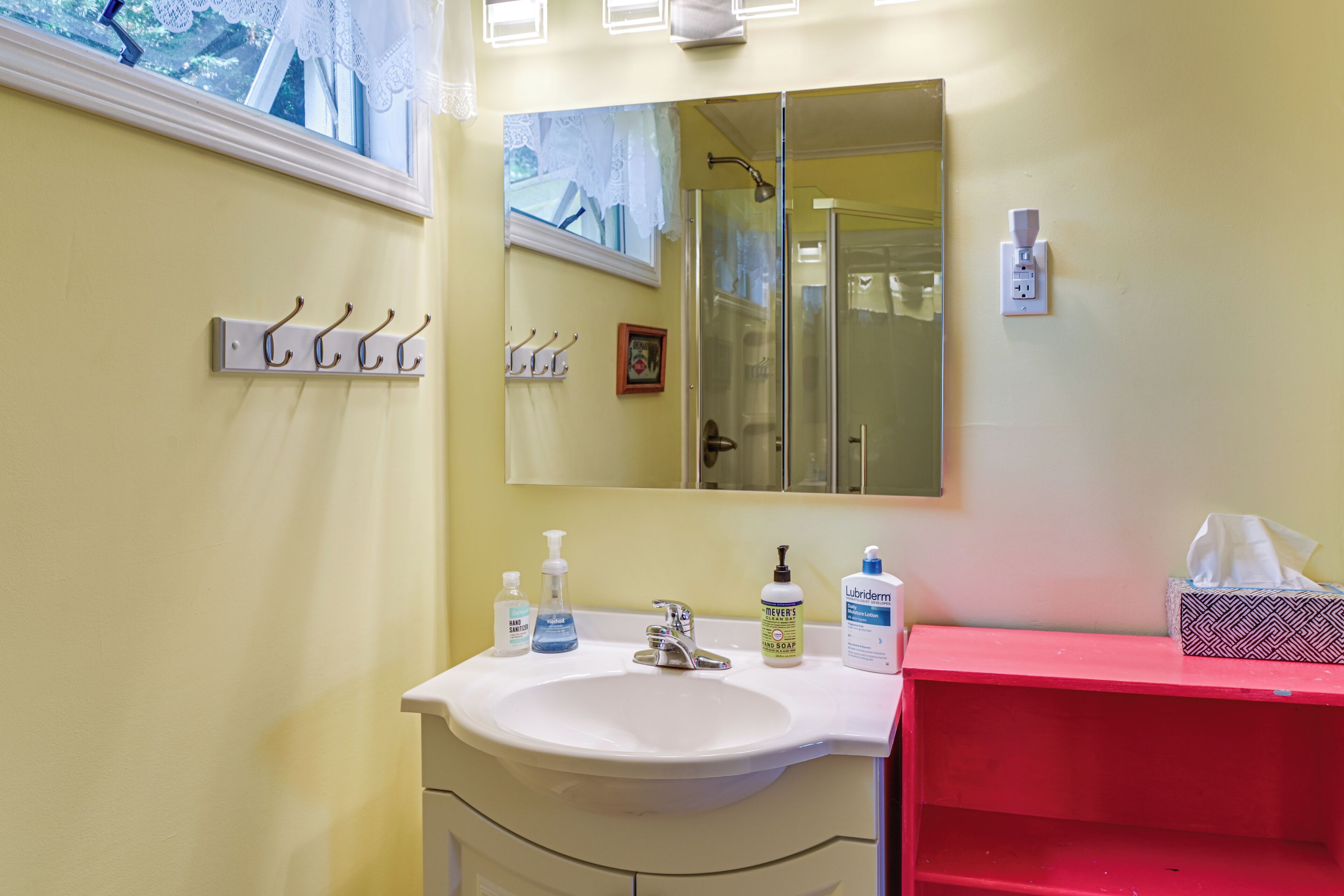 A bathroom with a white sink, a mirror, and a red vanity.