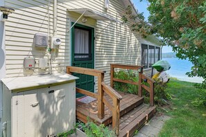A wooden deck with a green door leading to a house by a lake. - Dock & Rowboat: 'beechnut Bungalow' on Keuka Lake (Branchport)