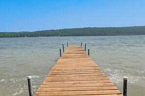 A wooden pier extending into calm waters with a forested hill in the background. - Dock & Rowboat: 'beechnut Bungalow' on Keuka Lake (Branchport)